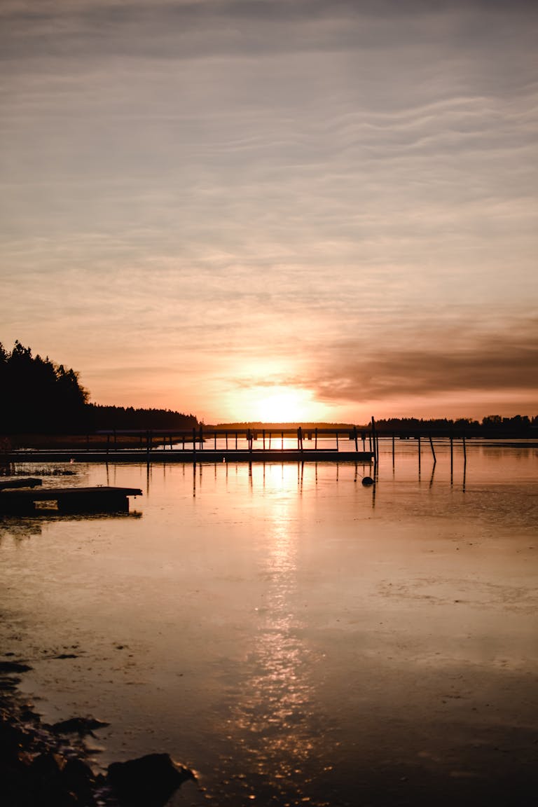 Beautiful sunrise over a tranquil lake in Helsinki, Finland with a scenic pier view.
