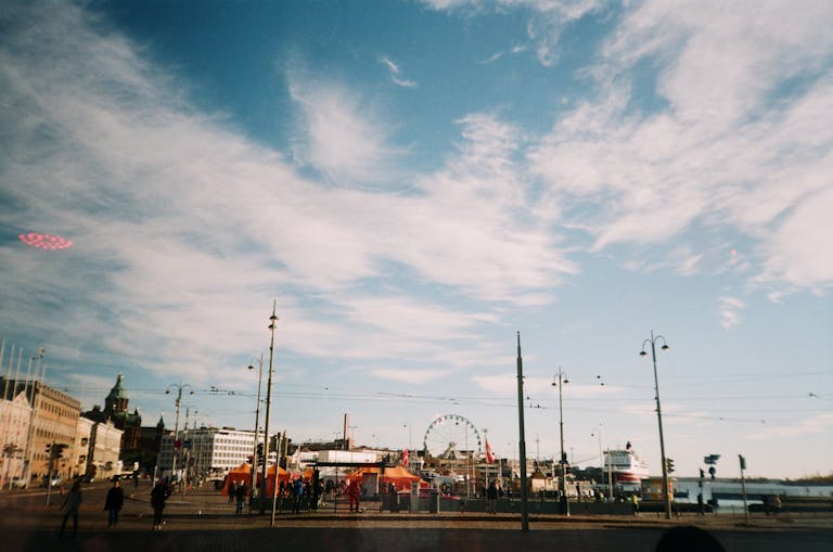 A ferris wheel in the Helsinki cityscape against a blue and cloudy sky.