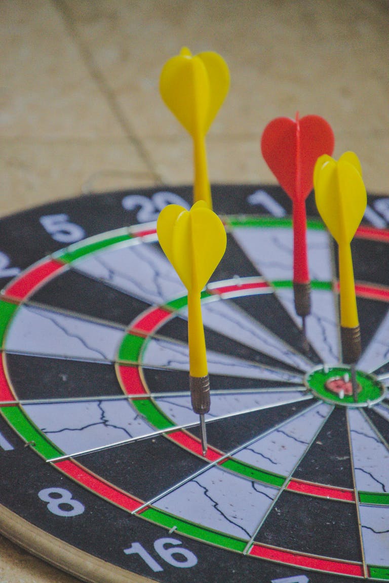 Colorful darts hitting the bullseye on a dartboard, capturing precision and focus.