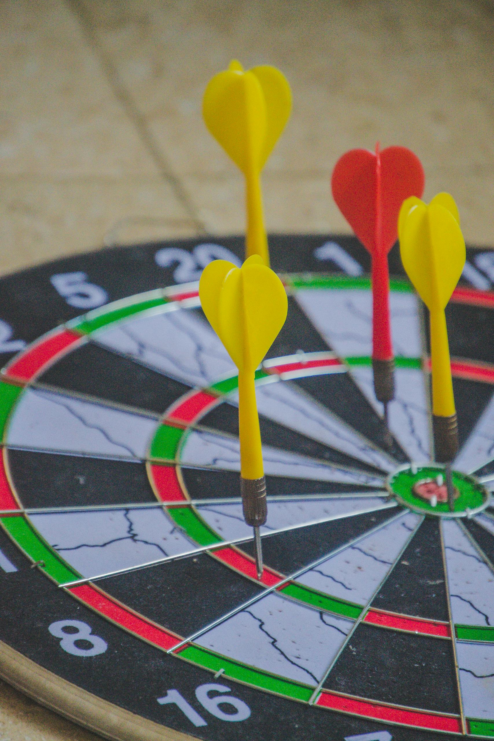 Colorful darts hitting the bullseye on a dartboard, capturing precision and focus.