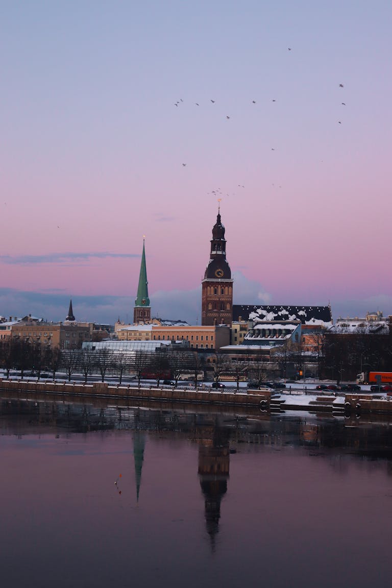 Captivating view of Riga's skyline during sunset with cathedral reflections on Daugava River.