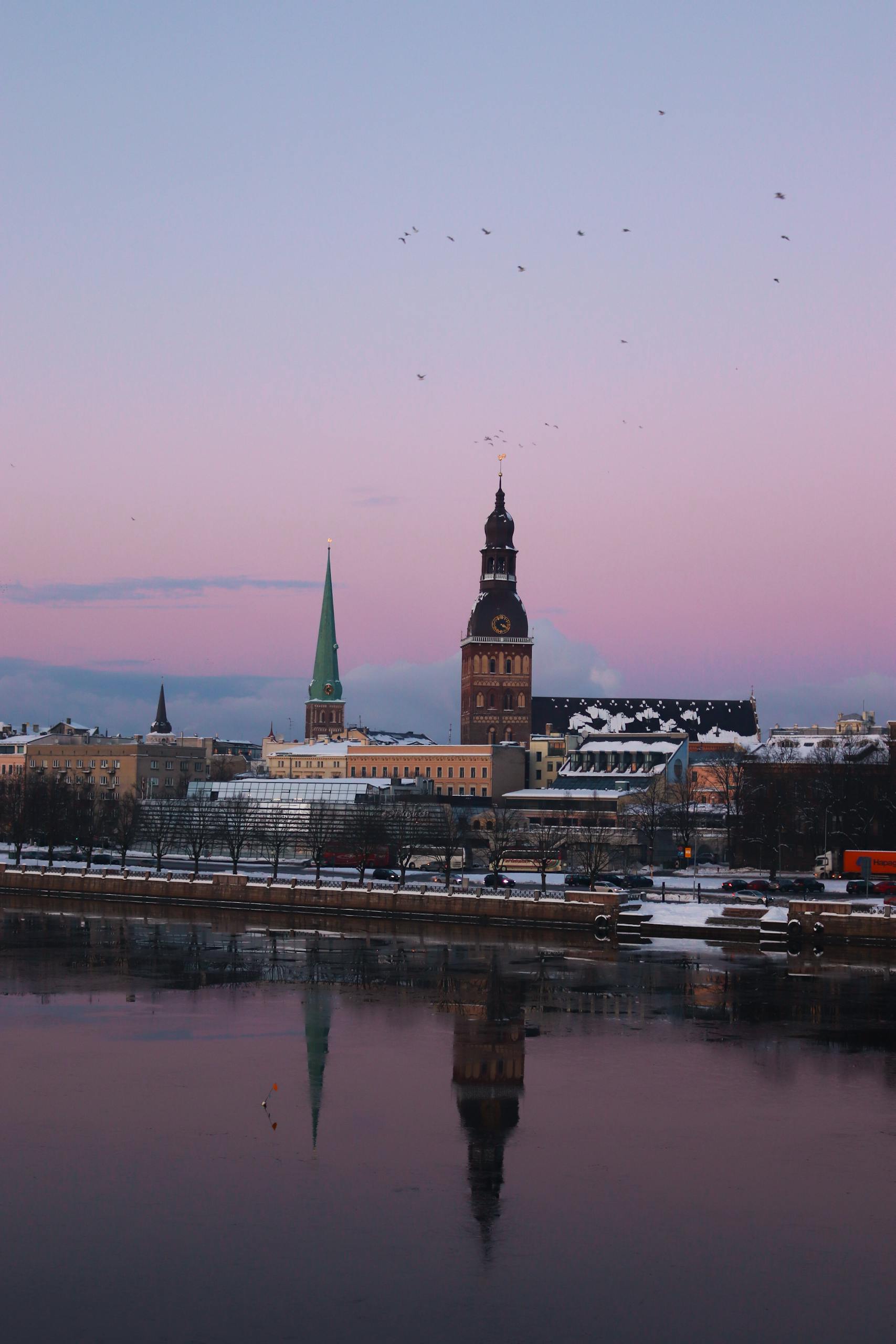 Captivating view of Riga's skyline during sunset with cathedral reflections on Daugava River.