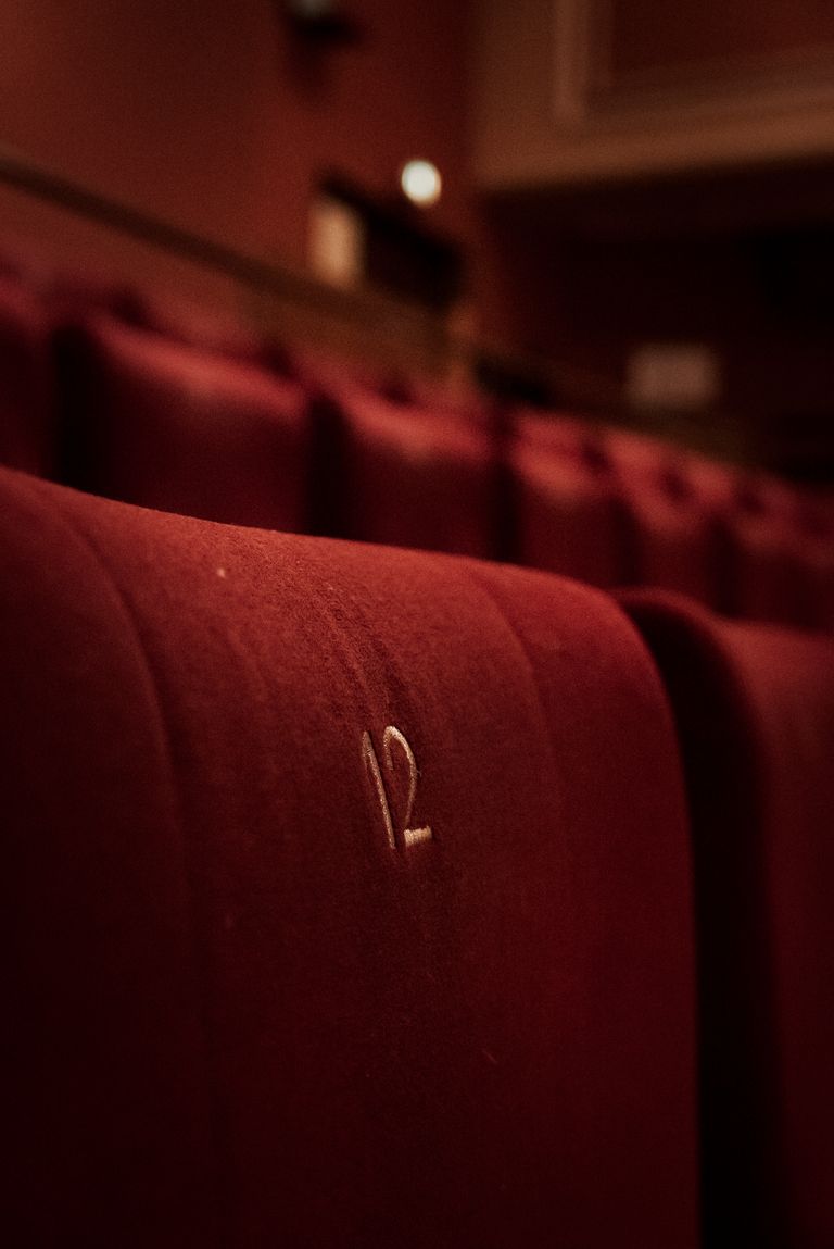 Close-up of red velvet cinema seats with the number twelve embroidered, creating a retro ambiance.