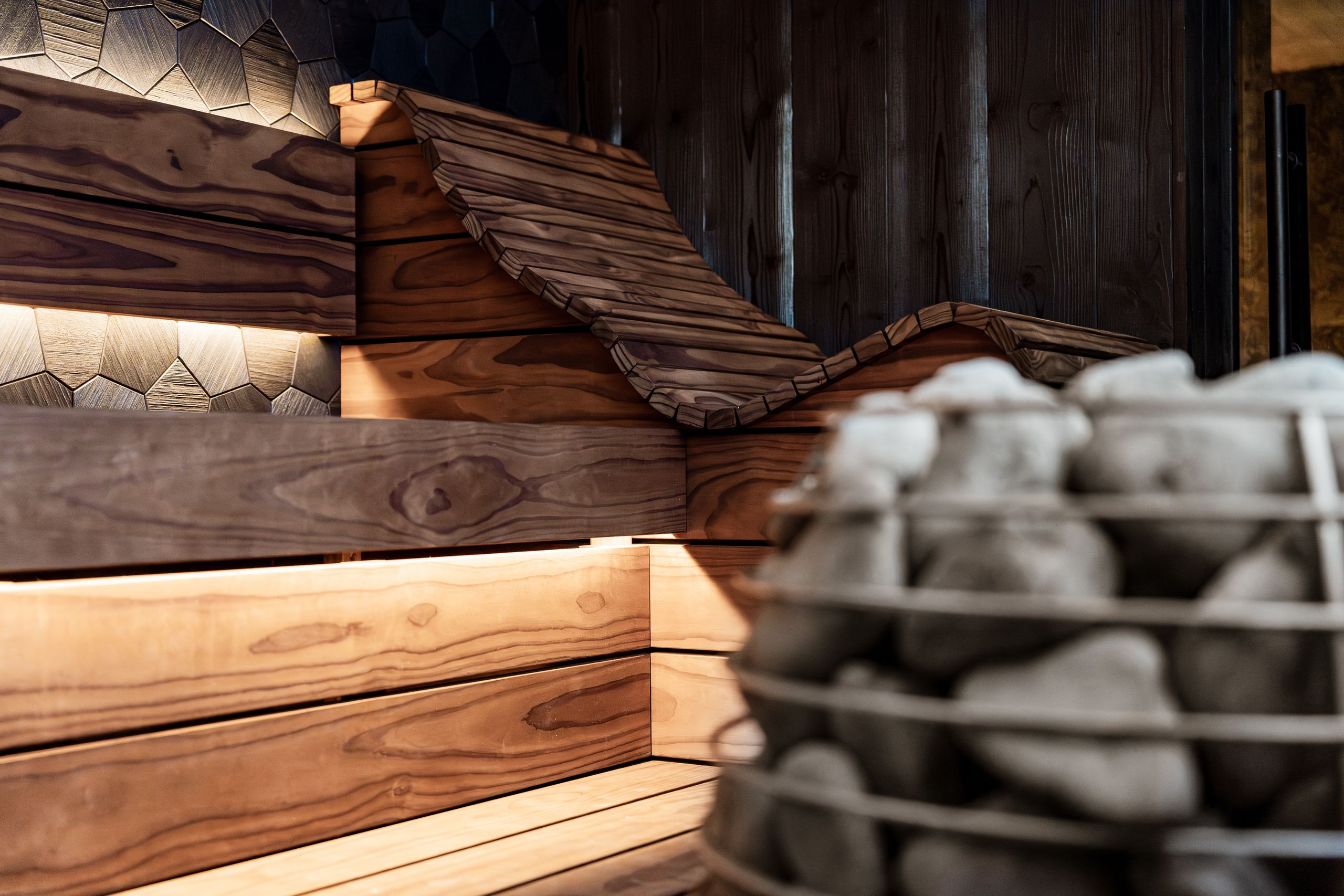 Explore the design of a stylish sauna featuring wood panels and a stone heater.